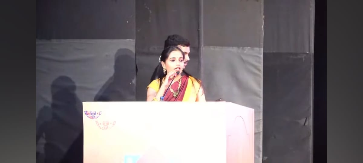 Yashaswee speaking at a cultural event podium